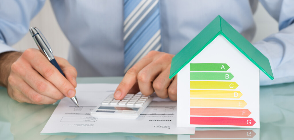 Close-up Of Businessman Calculating Energy Efficiency Rate Of House In Office