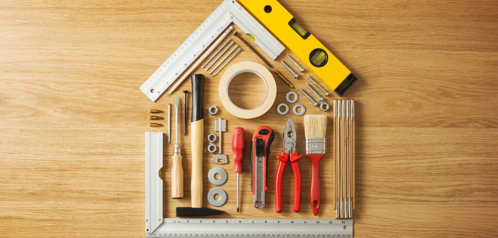 Conceptual house composed of DIY and construction tools on hardwood flooring, top view