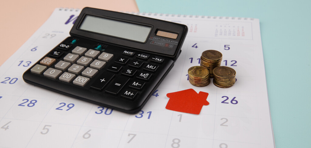 New house purchase, mortgage schedule reminder or real estate payment day, red house with calculator on white clean calendar.