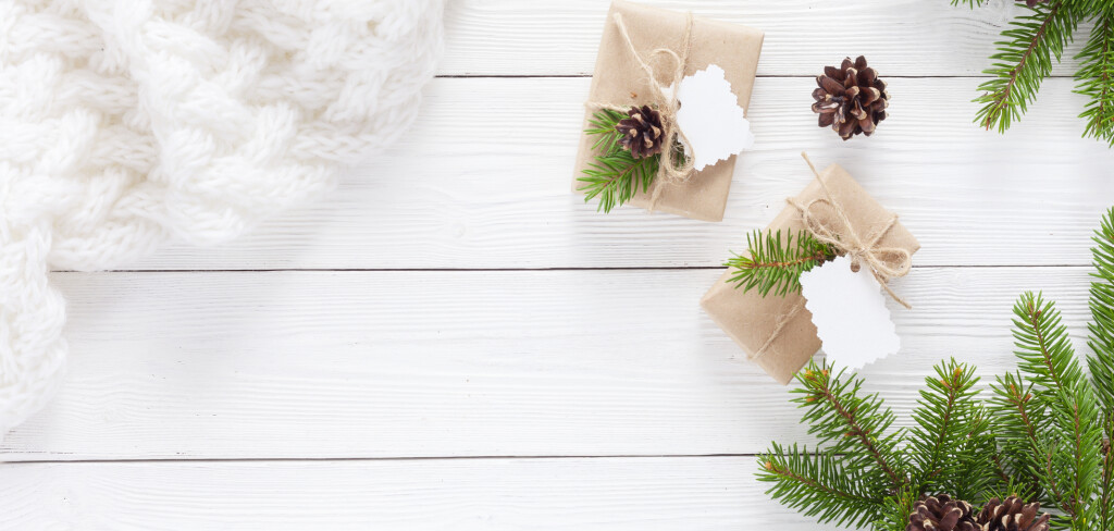 Christmas gifts and white scarf on a white wooden table with fir branches