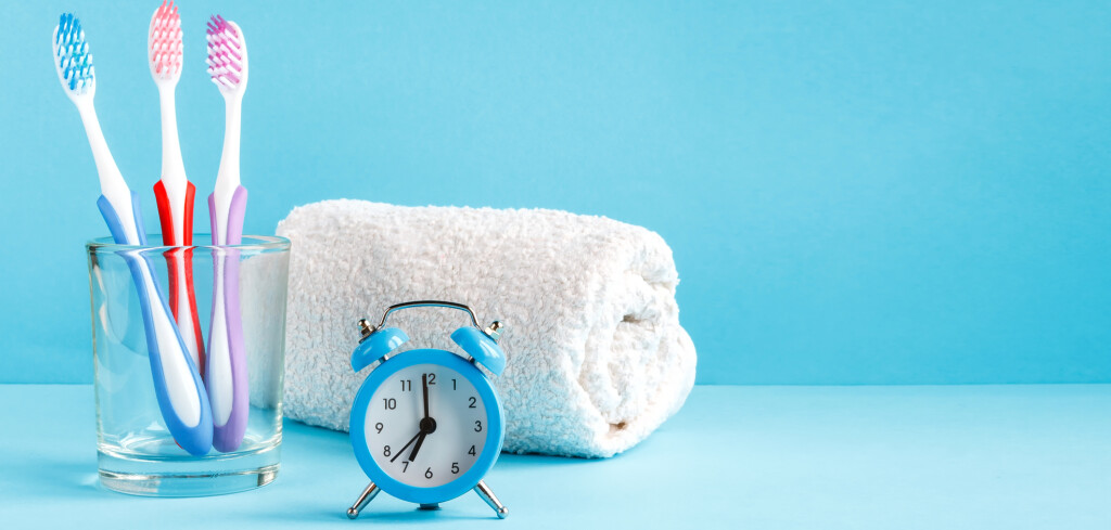 Healthy teeth. Toothbrush in a glass and toothpaste and bath towel on a table in the bathroom on a blue background. Design, health care, hygiene health and fresh breath