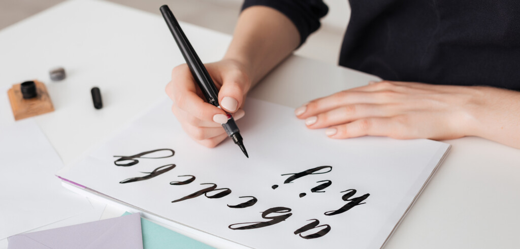 Portrait of young woman hands writing alphabet on paper on desk  isolated