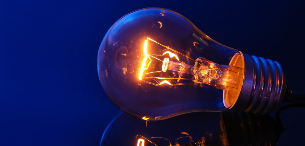 Glowing light bulb on dark color background